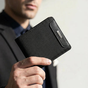 Black textured bifold wallet held in hand, showing front panel and side card slot