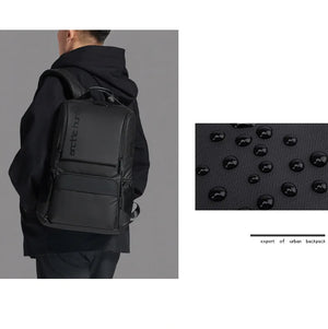 Black travel backpack with textured front panel and padded back, rear view