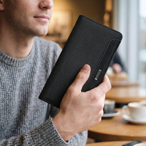 Black long bifold wallet held in hand, showing textured finish and front panel.