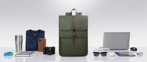 Green backpack with desk items beside it, highlighting spacious commuter storage
