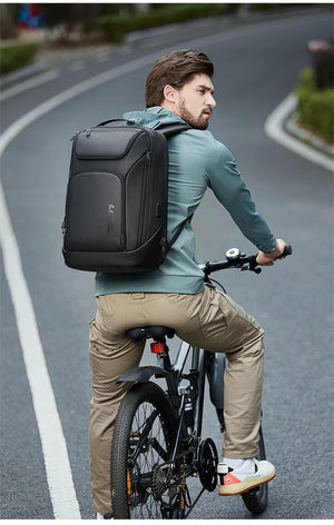 Black waterproof travel backpack on bicycle rider, front pocket and adjustable straps