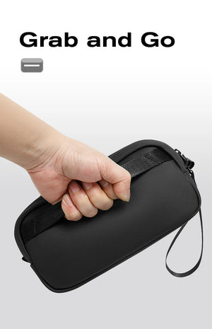 Black tech storage bag held in hand, compact zippered case with wrist strap