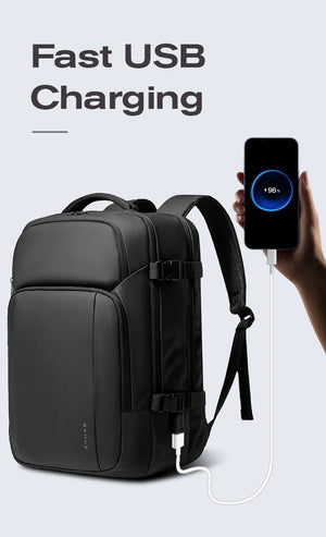 Black travel backpack with front pocket and USB charging port connected to a power cable.