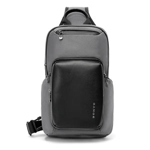 Grey compact crossbody bag with front flap pocket and top handle, side zipper details