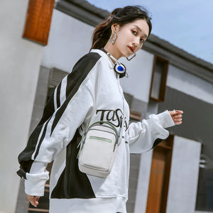 Small crossbody bag with white body, green accents, and adjustable shoulder strap