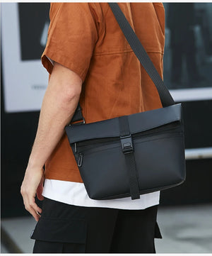 Black rectangular messenger bag worn crossbody with front buckle strap and flap