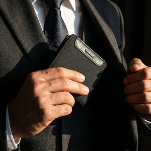 Black textured bifold card wallet being held at a suit pocket