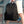 Black backpack held by top handle with side straps and front zipper pocket