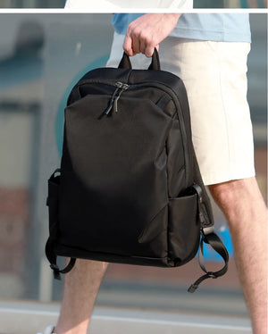 Black backpack held by top handle with side straps and front zipper pocket