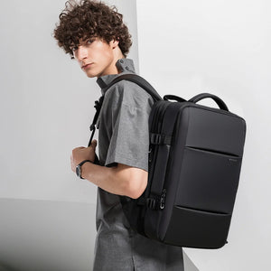 Black travel backpack worn on model with front panel zipper and padded shoulder straps