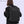 Black travel backpack on a person from back view with padded straps and top handle