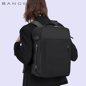Black travel backpack on a person from back view with padded straps and top handle