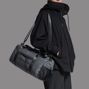 Waterproof duffel bag in black with long strap, zip front panel, and side pockets