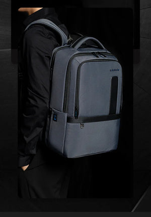 Gray waterproof travel backpack worn by person, front zip and side pocket details