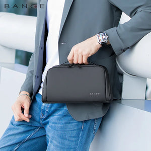 Black waterproof toiletry bag carried by a handle with zippered front pouch and logo.