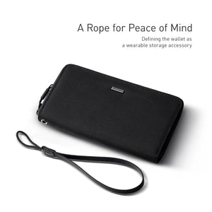 Long clutch wallet with wrist strap, textured black fabric and minimal front tab detail