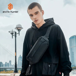 Black crossbody bag worn across chest over a black hoodie; diagonal strap and zip pocket.