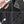 Black sling bag detail: textured strap, zipper pull, and metal key clips