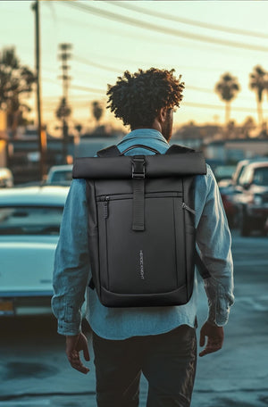 Black roll-top backpack on a person, secured with front webbing straps