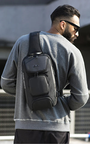 Black crossbody sling bag worn on back, with top handle and front organizer pockets.