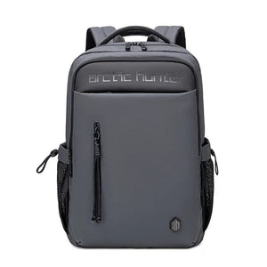 Grey waterproof travel backpack with logo badge, front zip pocket, and side pulls