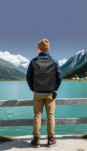 Black travel backpack on a person standing by a lake with adjustable shoulder straps