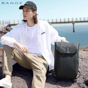 Grey roll-top waterproof backpack worn on shoulder, front flap and rolled top closure