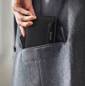 Black slim bifold wallet in front jeans pocket, textured exterior and logo tab.