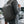 Black backpack worn in side profile with structured front panel and padded straps