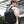 Black travel backpack with top handle and adjustable shoulder straps, worn in transit