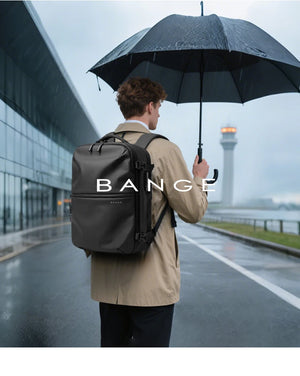 Black travel backpack worn outdoors under an umbrella, with top handle and side buckles visible