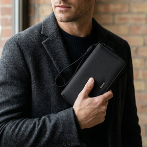 Men's long clutch wallet with wrist strap, textured black fabric, held in hand